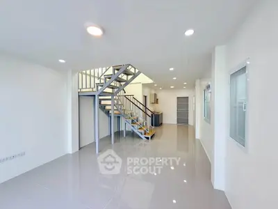 Spacious modern living room with sleek staircase and open layout, perfect for contemporary living.