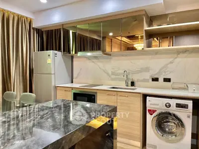 Modern kitchen with marble countertop, washing machine, and stainless steel fridge