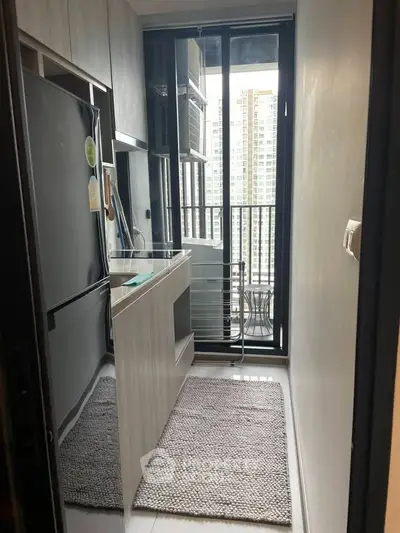 Compact kitchen with modern appliances and balcony view in high-rise apartment.