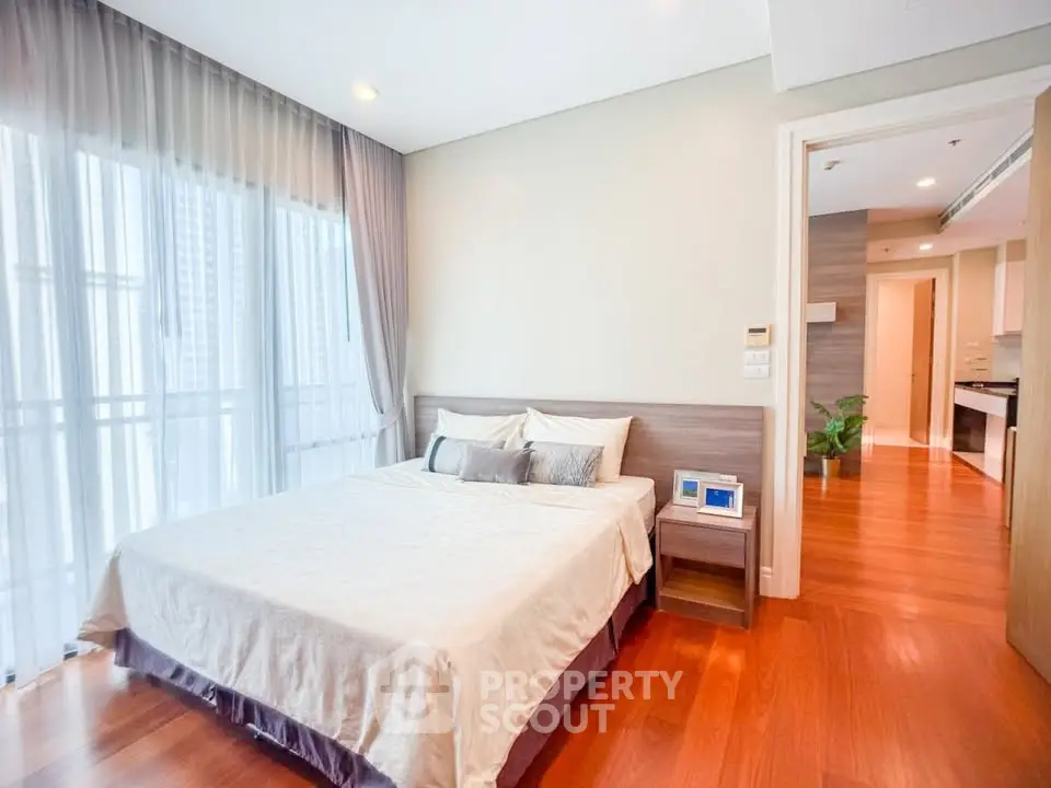 Spacious bedroom with wooden flooring and large windows in modern apartment