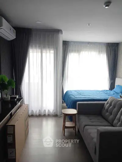 Modern studio apartment with cozy living area and large windows