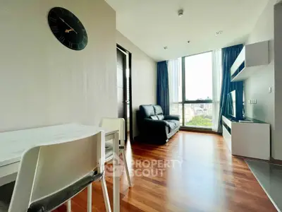 Modern living room with wooden flooring, large window, and stylish furniture.