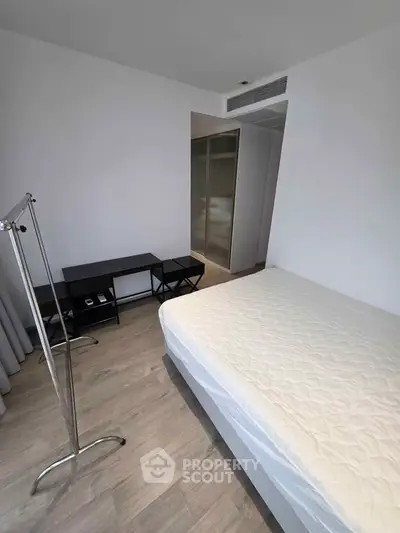 Spacious bedroom with modern minimalist design and ample natural light.