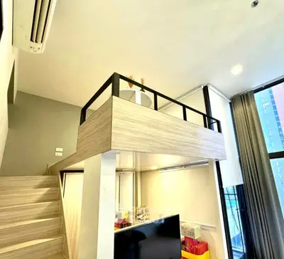 Modern loft apartment with mezzanine and large windows offering city views.