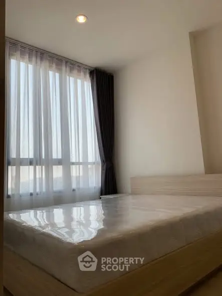 Modern bedroom with large window and natural light, featuring a minimalist design and cozy atmosphere.