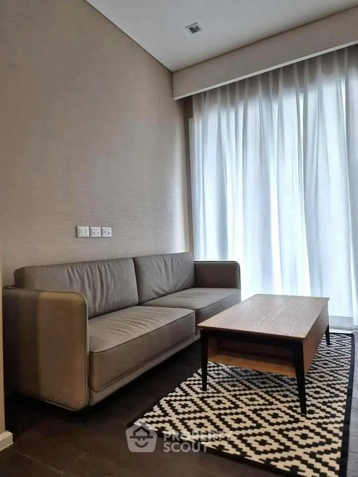 Modern living room with stylish sofa and coffee table, featuring elegant curtains and a geometric rug.