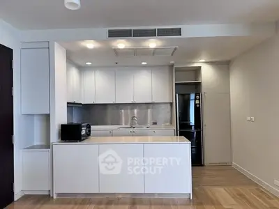 Modern kitchen with sleek white cabinetry and stainless steel appliances in a contemporary apartment.