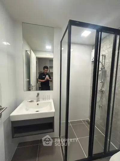 Modern bathroom with sleek shower enclosure and stylish sink in contemporary apartment.