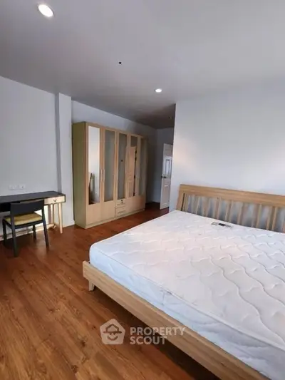 Spacious bedroom with wooden flooring and modern furniture, perfect for a cozy living experience.