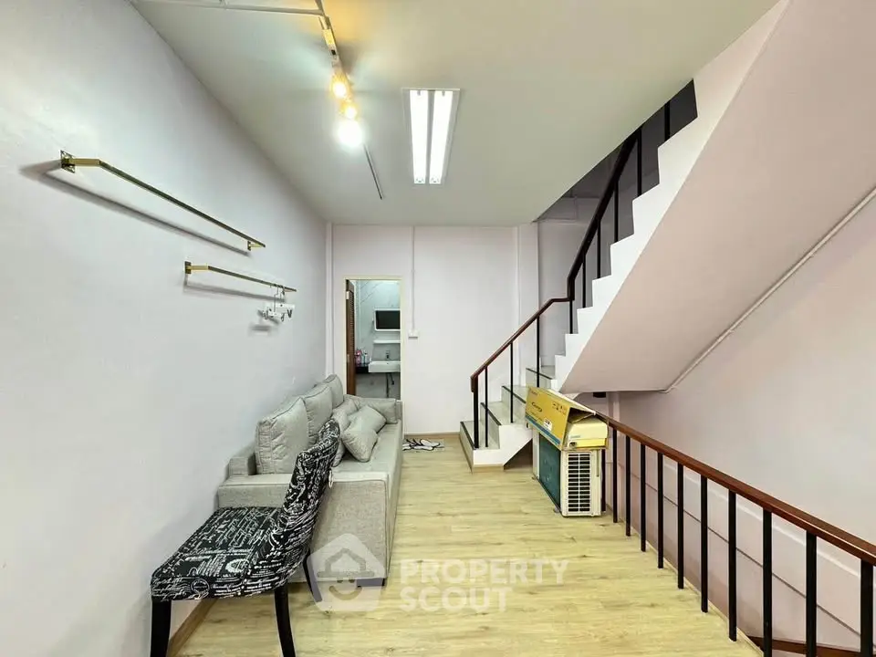 Modern duplex living room with stylish staircase and cozy seating area.