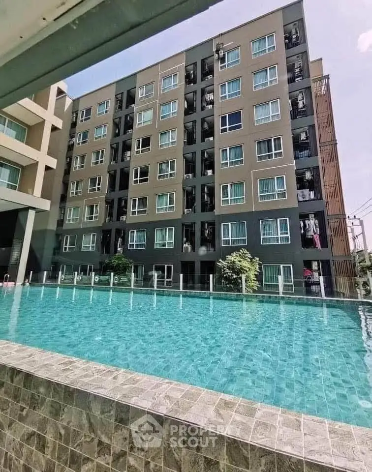 Modern apartment building with a sparkling pool and spacious balconies.