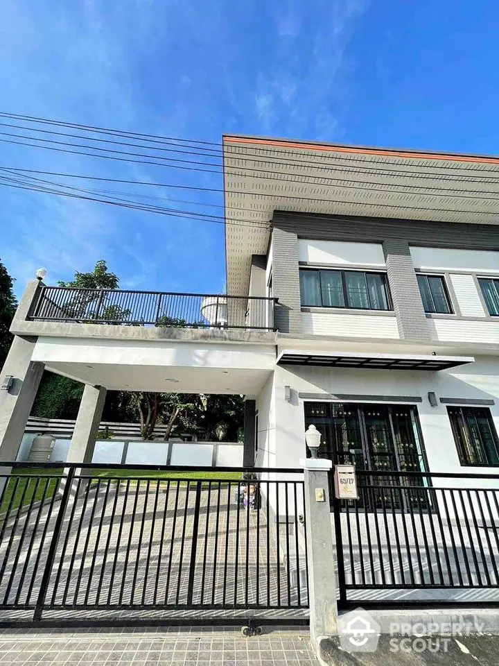 Modern two-story house with spacious balcony and gated driveway