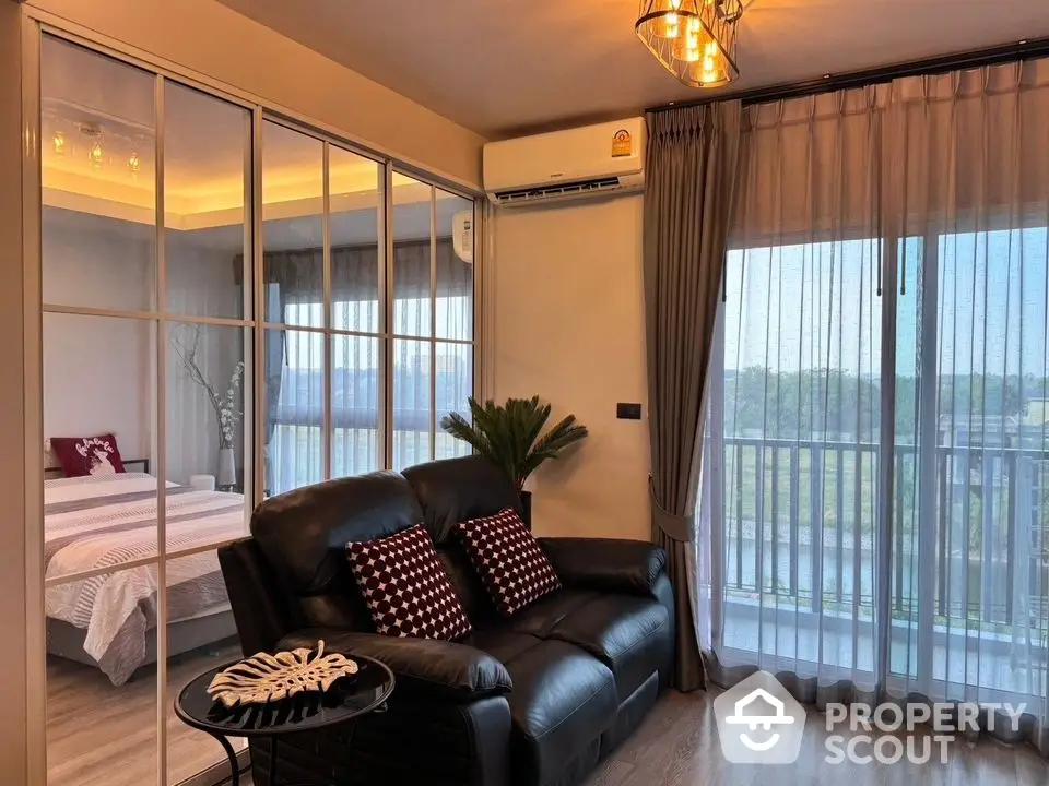 Modern living room with leather sofa and glass partition to bedroom, featuring scenic balcony view.