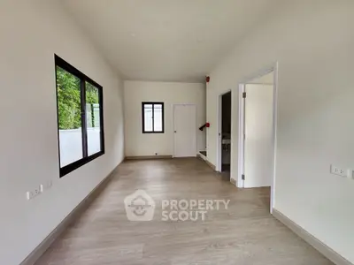 Spacious and bright room with large windows and modern flooring, perfect for versatile use.