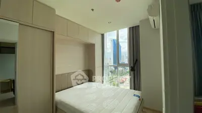 Modern bedroom with large window offering stunning city view in high-rise apartment.