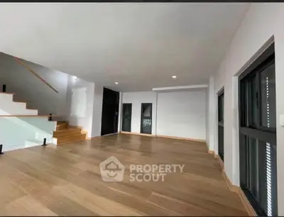 Spacious modern living room with wooden flooring and staircase, ideal for contemporary living.