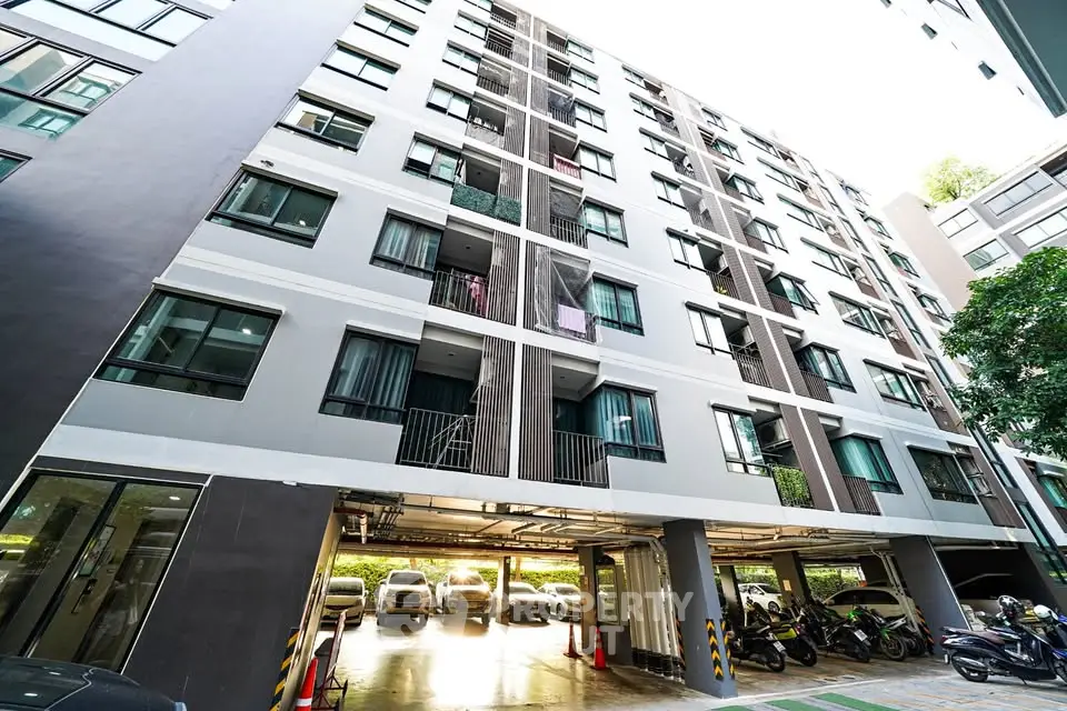 Modern apartment building with parking area and lush greenery