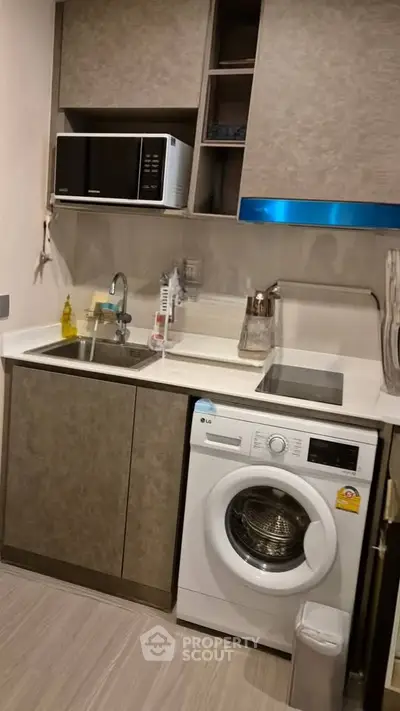 Compact modern kitchen with washing machine and microwave, ideal for urban living.