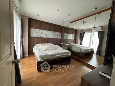 Spacious bedroom with mirrored wardrobe and elegant wooden flooring