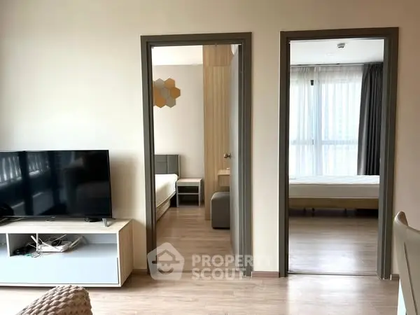 Modern apartment interior with two bedrooms and a cozy living area featuring a flat-screen TV.