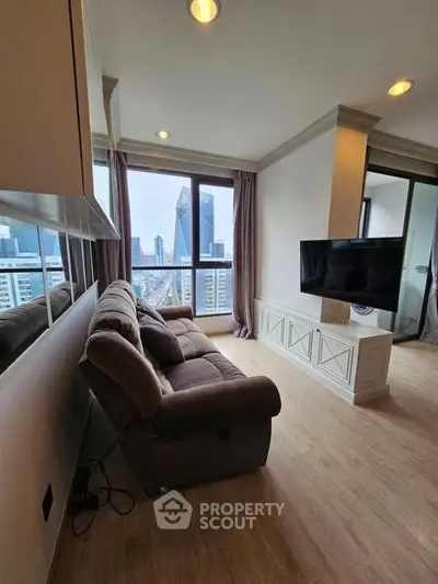 Modern living room with city view, featuring a cozy sofa and wall-mounted TV in a high-rise apartment.