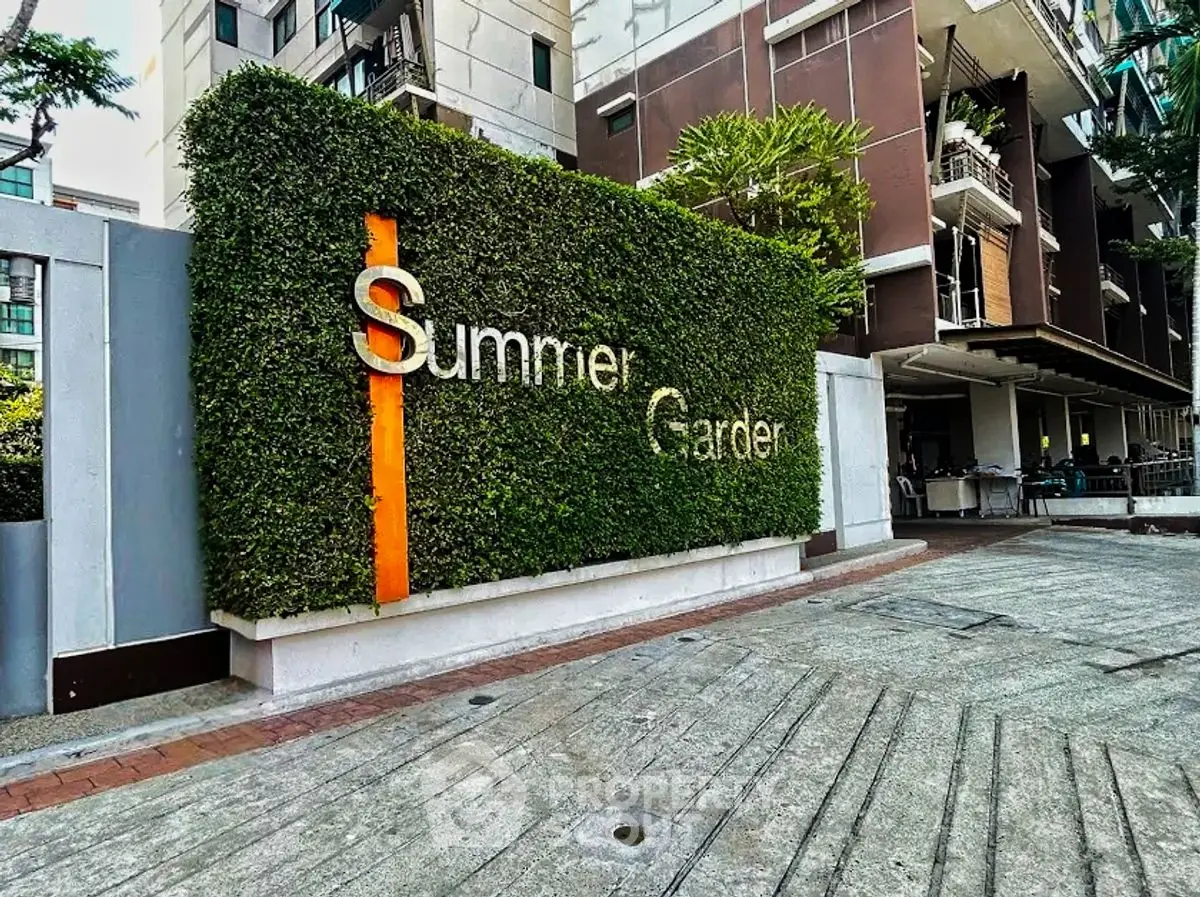 Modern apartment building entrance with lush greenery and stylish signage.