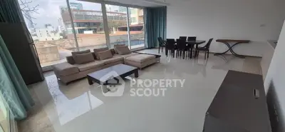 Spacious living room with modern furniture and large windows offering city views.