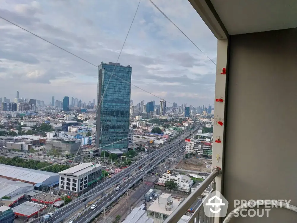 Stunning cityscape view from high-rise balcony overlooking urban skyline and busy highway.