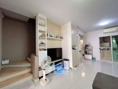 Modern living room with sleek design and open layout, featuring a staircase and stylish kitchen area.