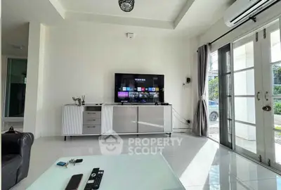 Modern living room with sleek TV setup and large windows for natural light.