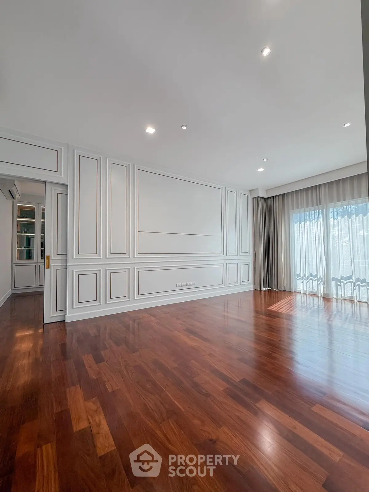 Spacious living room with elegant wood flooring and large windows for natural light.
