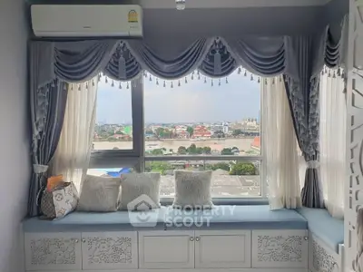 Charming window seat with elegant drapery and cityscape view, perfect for relaxation and enjoying the scenery.