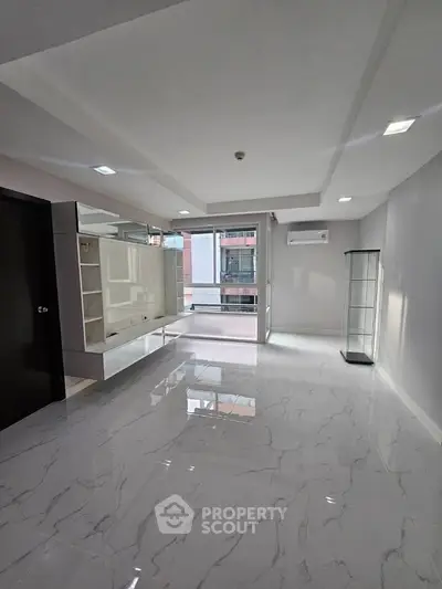 Spacious modern living room with glossy marble floors and large windows.