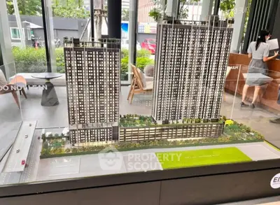 Modern architectural model of high-rise residential complex with lush landscaping.
