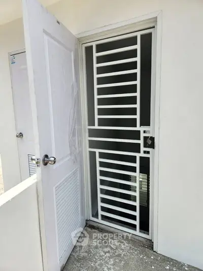 Modern white security door with sleek horizontal bars in a minimalist exterior setting.
