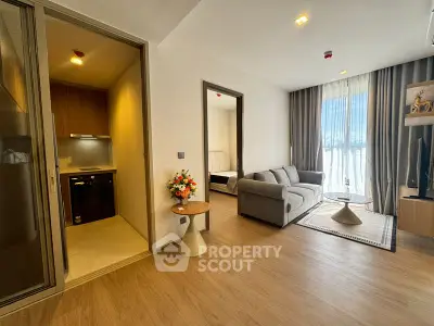 Modern living room with cozy sofa and stylish decor adjacent to compact kitchen area.