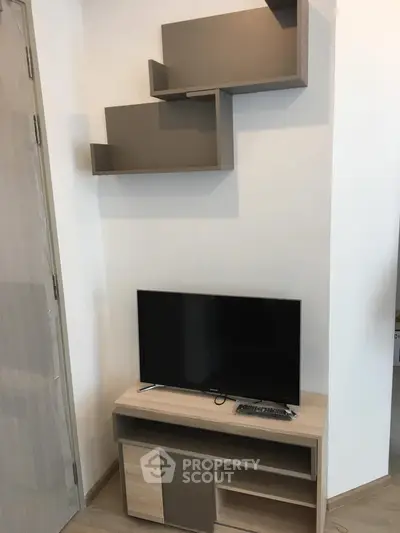 Modern living room with sleek TV stand and wall-mounted shelves in a stylish apartment.
