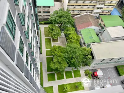 Stunning aerial view of modern apartment building with lush green courtyard and urban surroundings.