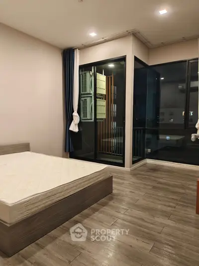 Modern bedroom with wooden flooring and large windows for natural light.