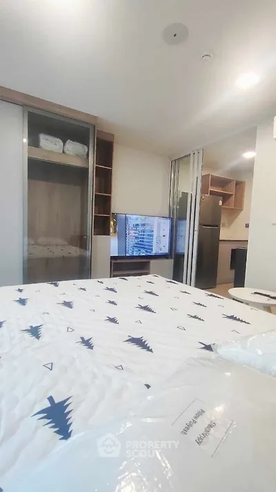 Modern bedroom with sliding closet doors and a view into a compact kitchen area.