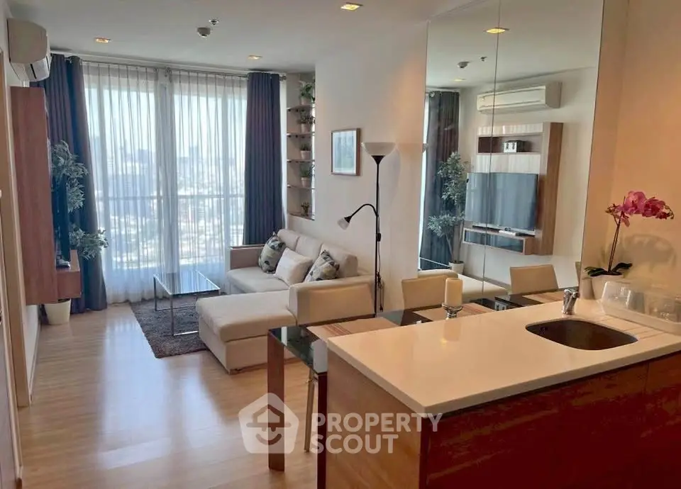 Modern living room with open kitchen, featuring floor-to-ceiling windows and stylish decor.