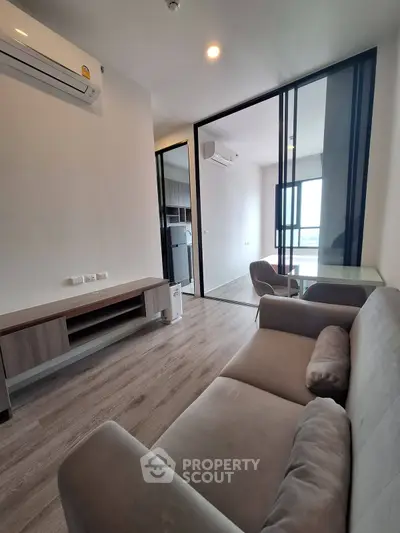 Modern living room with sleek design and glass partition, featuring a cozy sofa and air conditioning.