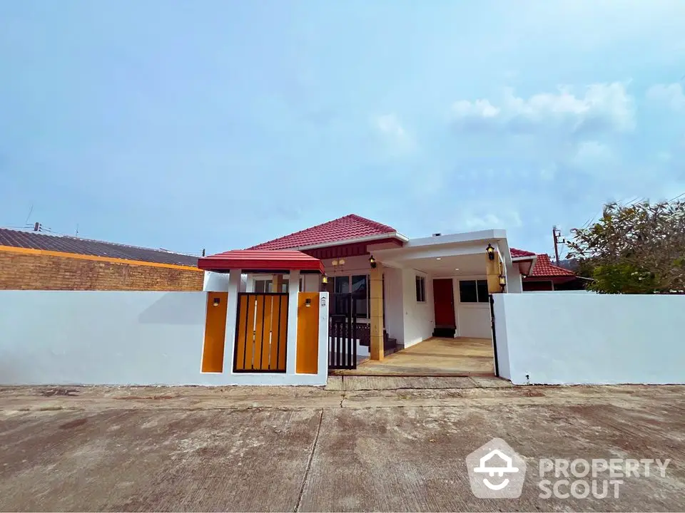 Charming single-story house with red roof and gated entrance, perfect for family living.