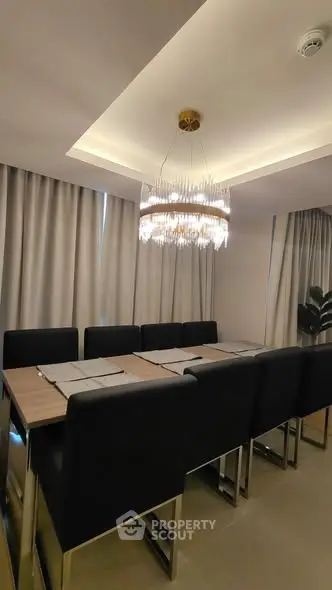 Elegant dining room with modern chandelier and sleek black chairs around a wooden table.