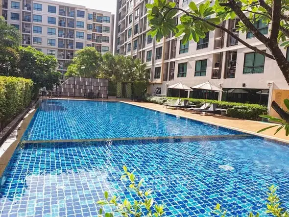 Luxurious apartment complex with sparkling blue swimming pool and lush greenery.