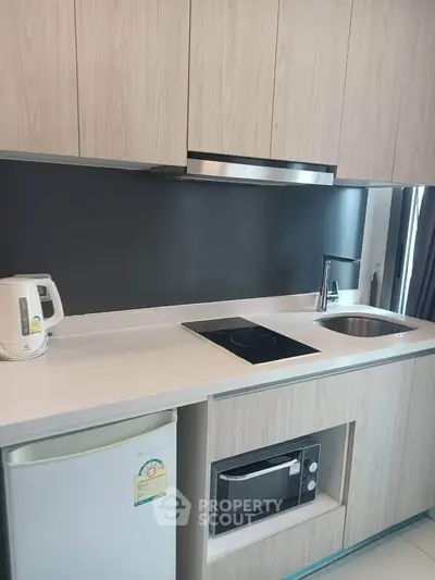 Modern kitchen with sleek cabinetry, induction cooktop, and compact appliances in a stylish apartment.