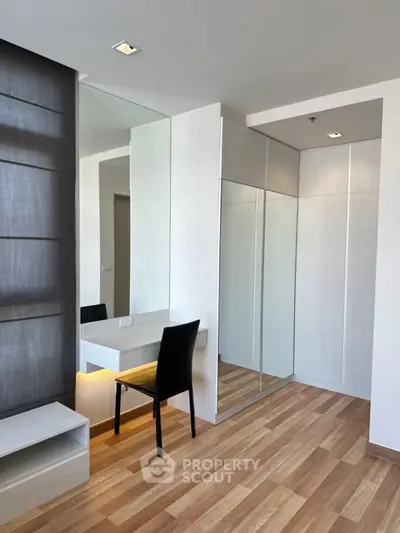 Modern minimalist bedroom with mirrored wardrobe and wooden flooring