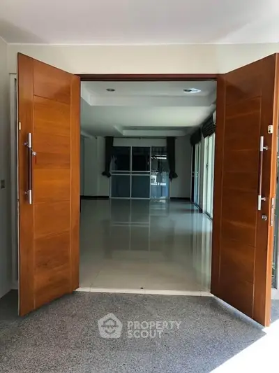 Spacious entrance leading to a bright and open living area with wooden double doors.