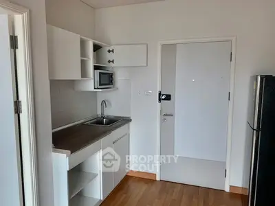 Compact kitchen with modern cabinetry and built-in microwave in a cozy apartment.