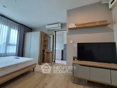 Modern bedroom with wooden flooring, large window, and sleek furniture in a stylish apartment.